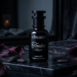 Elwane Tonka Royale perfume bottle on a dark surface with purple flowers.